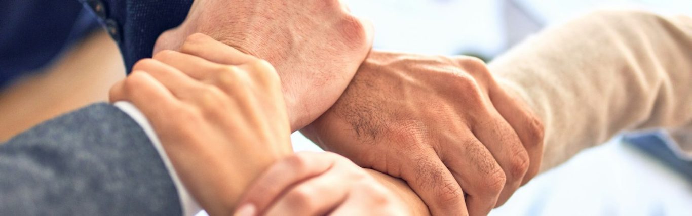 Hände verschiedener Personen, die sich überlappen und symbolisch zusammenarbeiten.